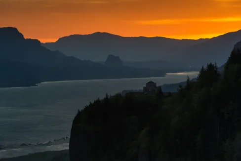 Orange sunset with large forested lake below